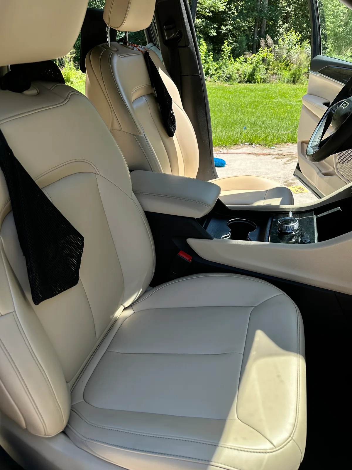 Luxury SUV front seat after detail — clean cream leather and center console